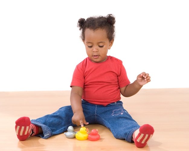 Hermosa chica africana jugando con tres patos de plástico