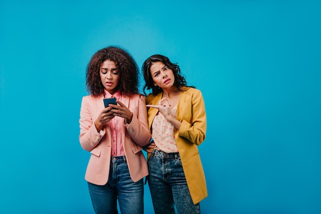 Hermosa chica africana usando internet móvil Foto de estudio de mujer latina con chaqueta amarilla