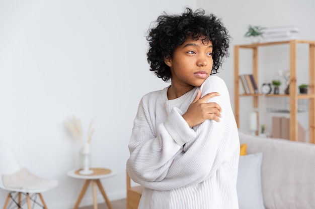 Hermosa chica afroamericana con peinado afro en casa interior Joven mujer africana con cabello rizado en la sala de estar Concepto de vida doméstica de personas étnicas de belleza