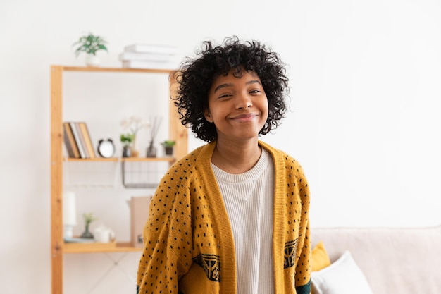 Hermosa chica afroamericana con peinado afro sonriendo en casa interior Joven mujer africana con cabello rizado riendo en la sala de estar Libertad felicidad despreocupada gente feliz concepto