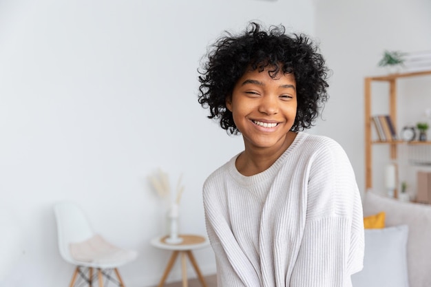 Hermosa chica afroamericana con peinado afro sonriendo en casa interior joven mujer africana con