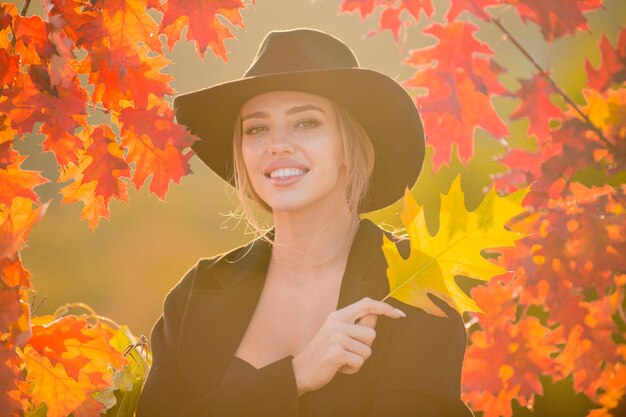 Hermosa chica al aire libre en otoño otoño joven recoge hojas de otoño amarillas en otoño belleza woma