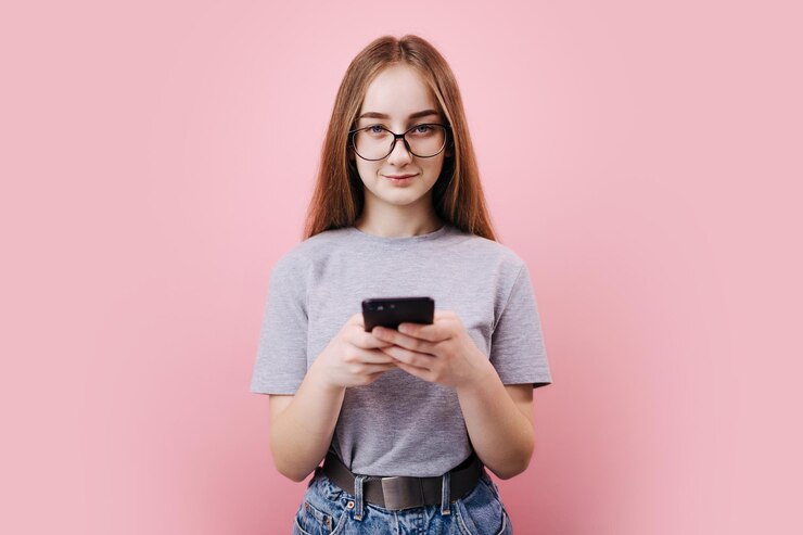 Hermosa chica en anteojos con smartphone en estudio