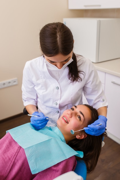 Hermosa chica con aparatos dentales en la recepción en el dentista.