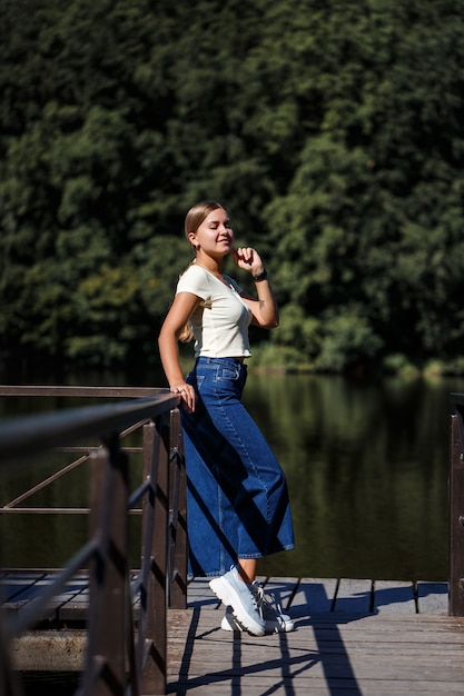 Una hermosa chica de apariencia europea. Una joven camina por el río. Vestida con jeans y una camiseta.