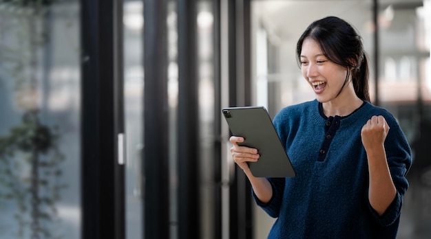 Hermosa chica asiática celebra con el éxito de la tableta digital pose feliz Comercio electrónico educación universitaria tecnología de Internet o concepto de pequeña empresa de inicio