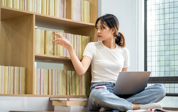 Hermosa chica asiática estudiando en la biblioteca