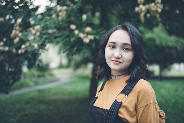 Hermosa chica asiática en un jardín, sonriendo