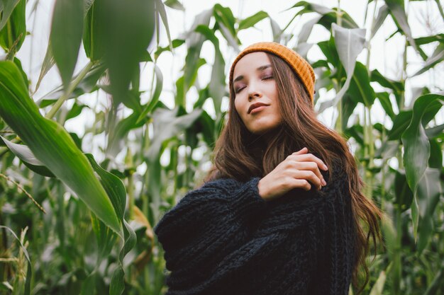 Hermosa chica asiática con los ojos cerrados en otoño campo de maíz