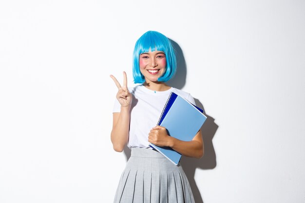 Hermosa chica asiática con peluca de anime azul, mostrando gesto de paz kawaii