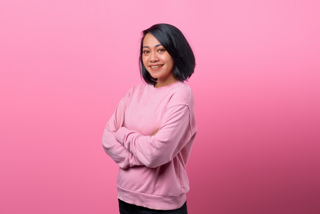 Hermosa chica asiática sonriendo ampliamente mirando hacia el futuro aislado sobre fondo rosa