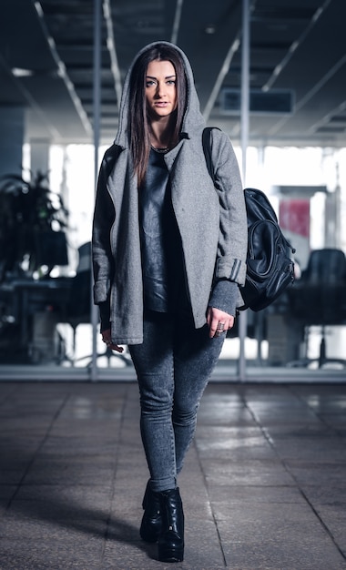 Hermosa chica atlética con cabello oscuro y hoddie y una mochila en el gimnasio