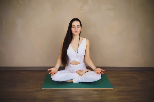 Hermosa chica atlética haciendo ejercicios de yoga disfruta de la meditación en casa. Sin estrés, hábito saludable, concepto de alivio de la ansiedad. Pose de loto.