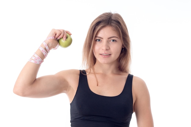 Hermosa chica atlética muestra los músculos apretando una manzana en su mano y borra directamente