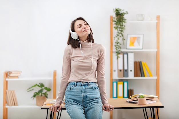 Una hermosa chica con auriculares escucha música y se para cerca del lugar de trabajo