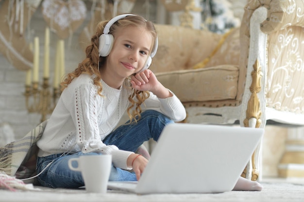 Hermosa chica en auriculares con laptop en Navidad