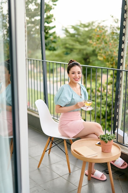 Hermosa chica en el balcón bebiendo té