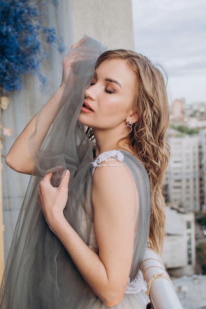 Hermosa chica en el balcón con un vestido gris