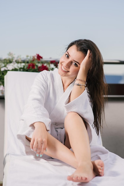 Hermosa chica en bata de baño relajarse en el balcón del hotel con hermosas vistas a las montañas