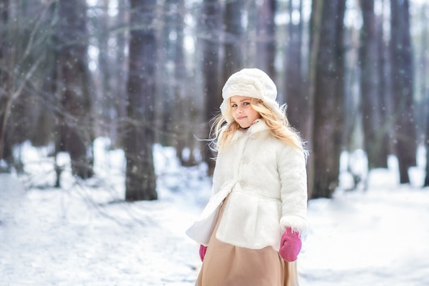 hermosa chica en una bata blanca en el bosque en invierno