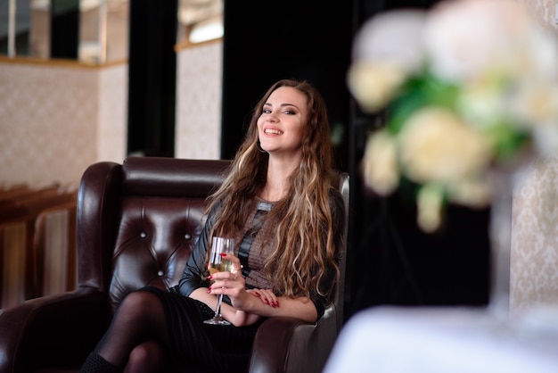 Hermosa chica bebiendo champán en el restaurante