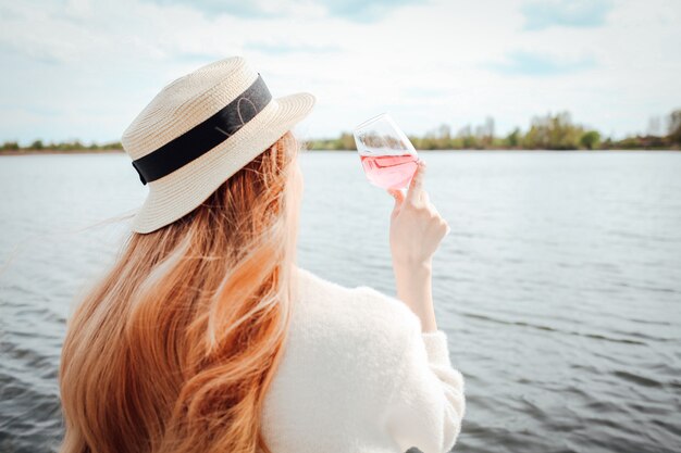 Hermosa chica bebiendo vino rosado en la playa