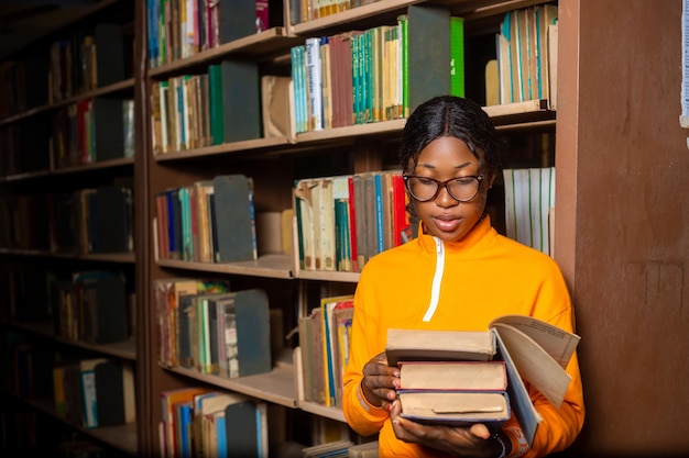 Hermosa chica en una biblioteca dama leyendo un libro en la biblioteca