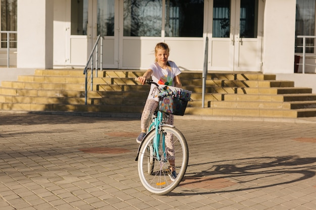 Hermosa chica en una bicicleta azul. Niña monta una bicicleta. vacaciones de verano. pasar tiempo con beneficio. bicicleta femenina con cesta