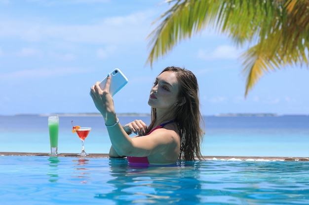 hermosa chica en bikini selfie en el teléfono