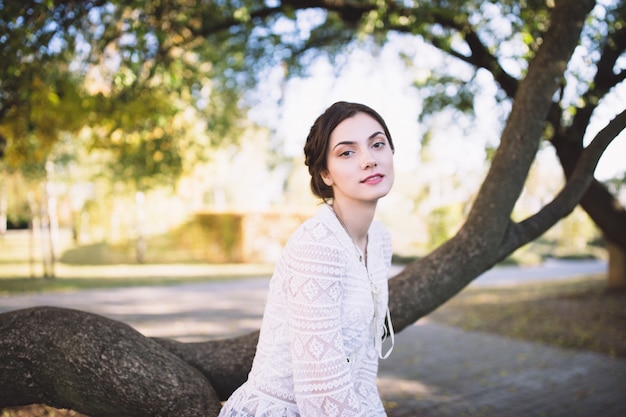 Hermosa chica en una blusa de encaje blanco en un parque de otoño