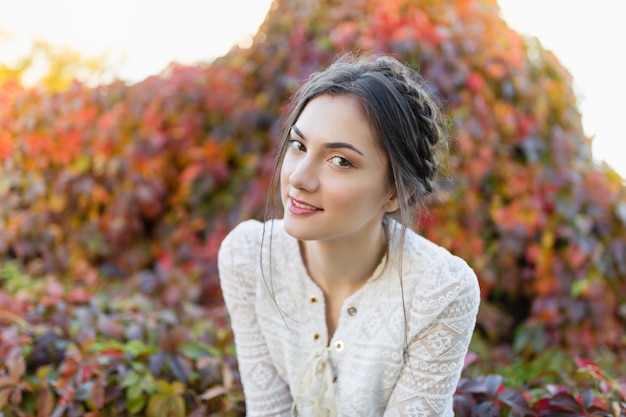 Hermosa chica en una blusa de encaje blanco en un parque de otoño