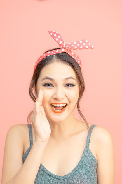 Hermosa chica con bonita sonrisa en estilo pin up sobre fondo rosa