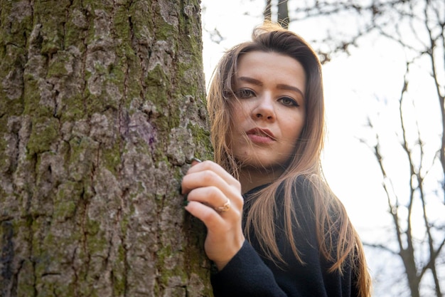 Hermosa chica en el bosque cerca de los árboles