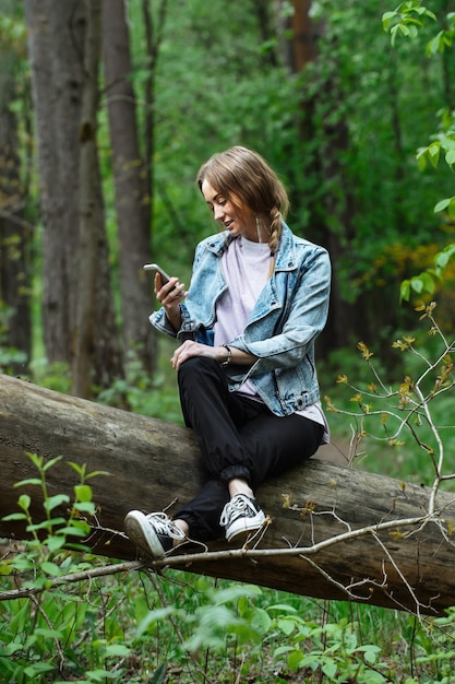 una hermosa chica en un bosque verde en un paseo hablando por teléfono en la estación cálida