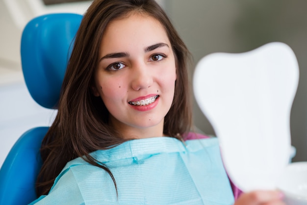 Foto hermosa chica con brackets sonríe en odontología.