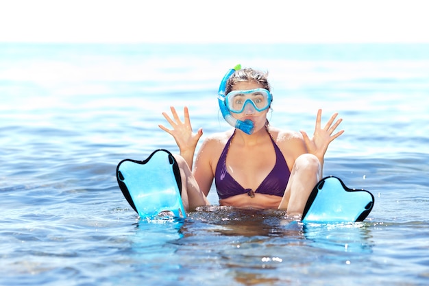 Hermosa chica bronceada con equipo de snorkel divirtiéndose en aguas poco profundas