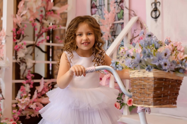 una hermosa chica de cabello castaño con un vestido blanco se para con un estudio de bicicletas flores