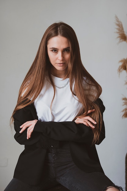 Hermosa chica con cabello largo se sienta en una silla en una hermosa habitación y posa para una foto