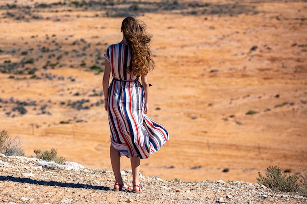 una hermosa chica de cabello largo con un vestido largo camina por un camino en el desierto en el oeste de australia