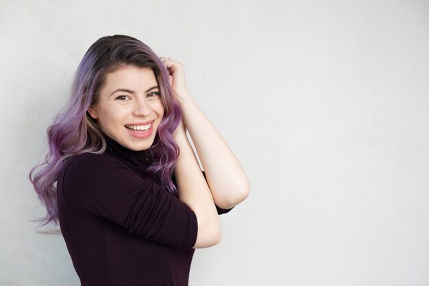 Hermosa chica con cabello morado sobre un fondo gris. Espacio para texto