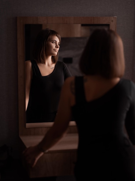 Foto hermosa chica con cabello oscuro le dio la espalda reflejo en el espejo