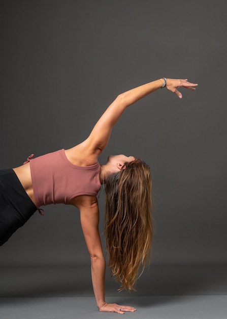 Una hermosa chica con cabello rubio que fluye está haciendo yoga