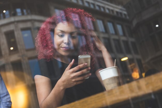 Hermosa chica en un café escribiendo en el teléfono inteligente