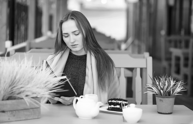 Hermosa chica en un café sentado y bebiendo té con postre