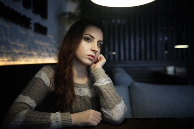 Hermosa chica en un café tomando una taza de café en una cena