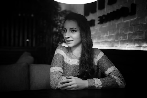 Hermosa chica en un café tomando una taza de café en una cena