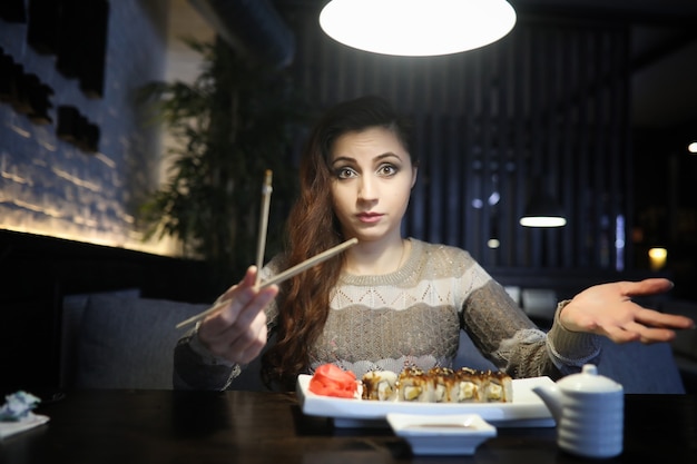 Hermosa chica en un café tomando una taza de café en una cena