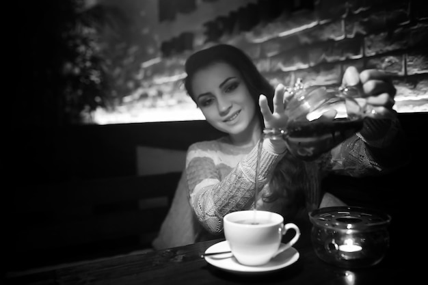 Hermosa chica en un café tomando una taza de café en una cena