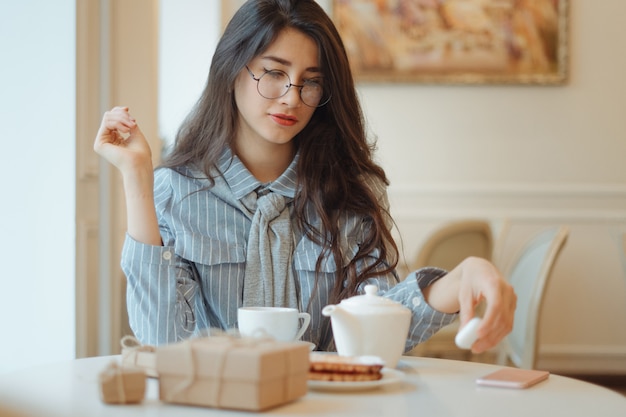 Hermosa chica en un café tomando té