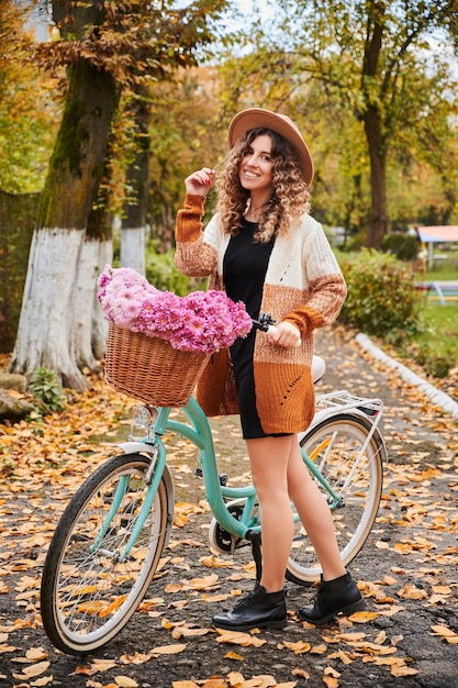 Hermosa chica en la calle con bicicleta retro de mujer